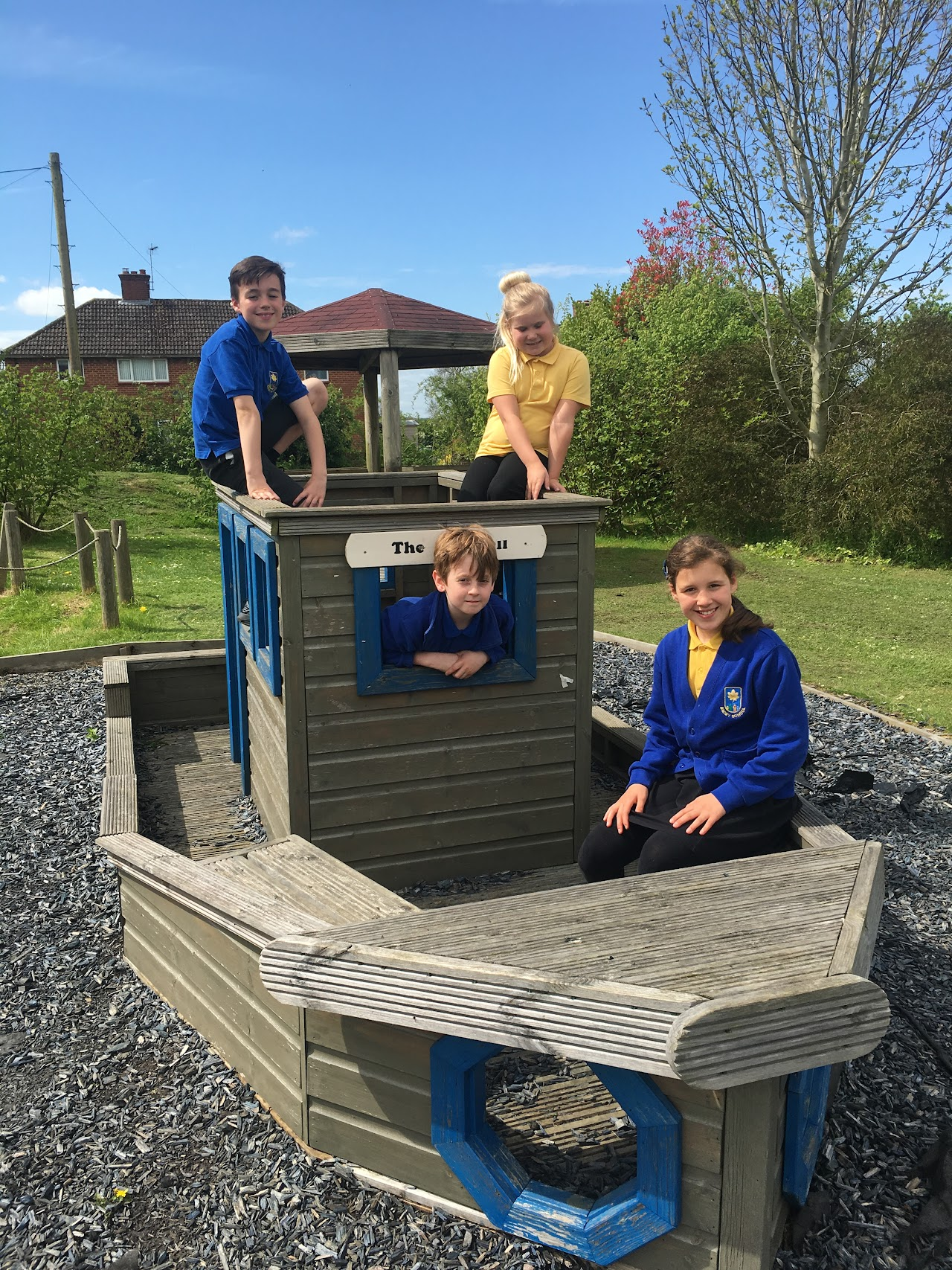 Four pupils wearing Badby uniform, including blue and yellow polo t-shirts and a blue branded cardigan