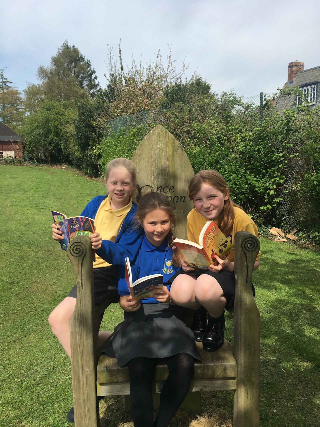 Three pupils wearing Badby uniform in a selection of blue and yellow, polo t-shirts and a blue cardigan